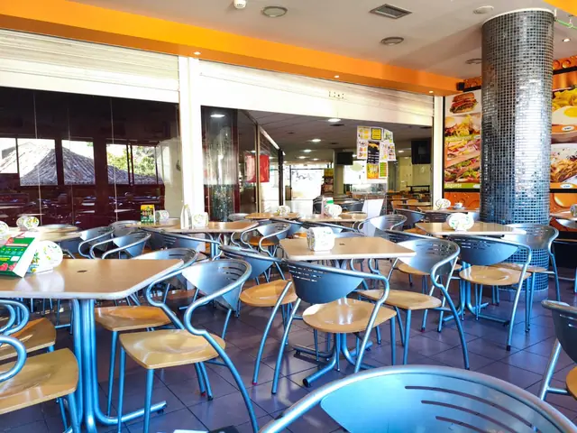 Sala da Docemania no Centro Comercial D. Dinis, com mesas de madeira, cadeiras metálicas e parede laranja