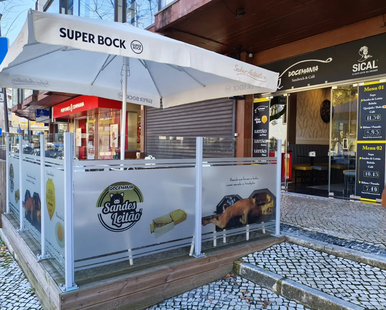 Esplanada da Docemania no Centro Comercial Maringá, com guarda-sol e para-ventos com o selo Sandes Leitão