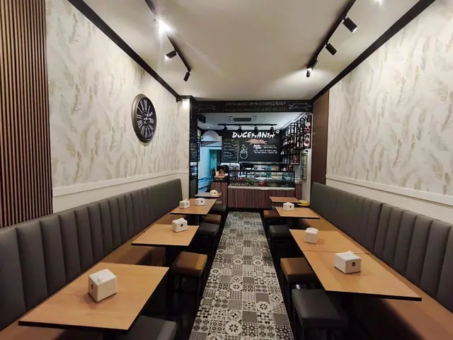 Sala com bancos corridos estofados, mesas de madeira e pavimento em mosaico hidráulico